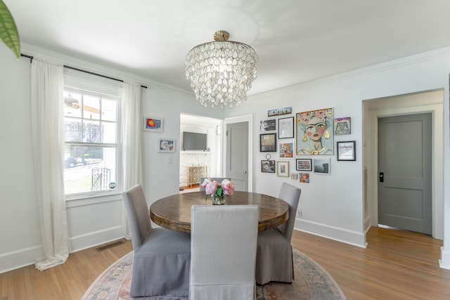 dining area with baseboards, light wood finished floors, visible vents, and a notable chandelier