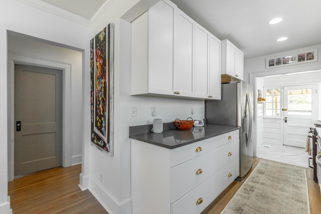 kitchen featuring crown molding, dark countertops, white cabinetry, wood finished floors, and stainless steel fridge