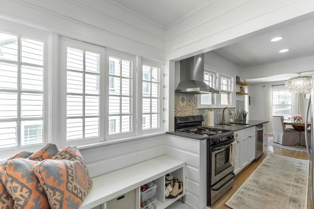 kitchen featuring decorative backsplash, stainless steel dishwasher, wall chimney range hood, a sink, and gas stove