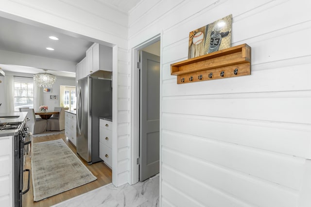 kitchen with white cabinets, gas range, freestanding refrigerator, marble finish floor, and recessed lighting