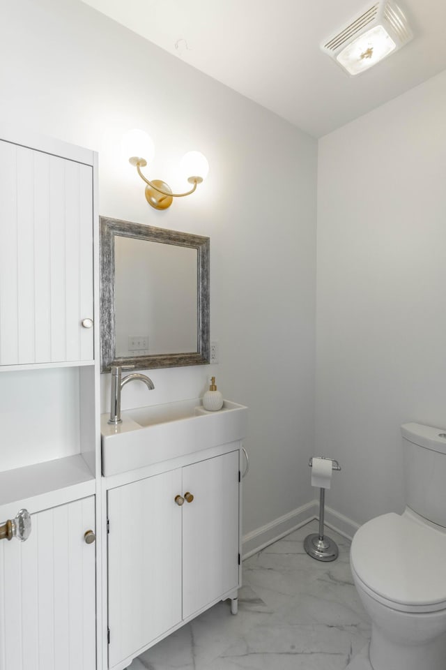 bathroom featuring toilet, vanity, visible vents, baseboards, and marble finish floor