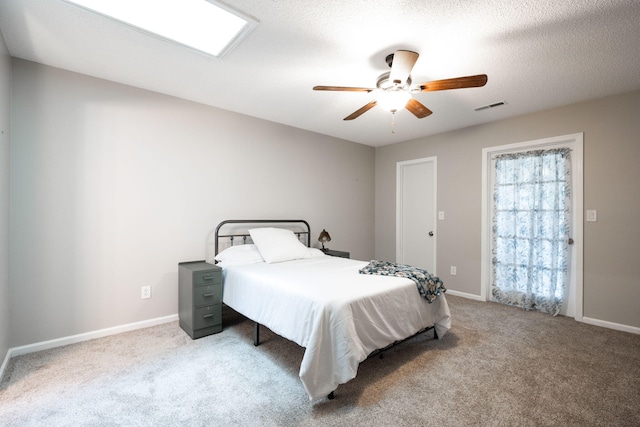 carpeted bedroom with baseboards, visible vents, ceiling fan, and a textured ceiling