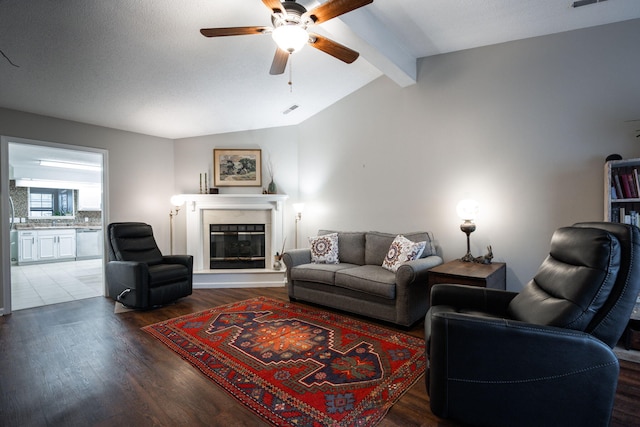 living room featuring visible vents, lofted ceiling with beams, a ceiling fan, a glass covered fireplace, and wood finished floors