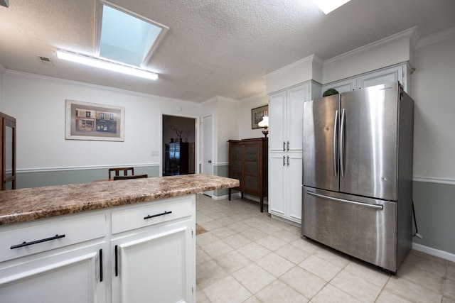 kitchen featuring a skylight, crown molding, visible vents, freestanding refrigerator, and white cabinets