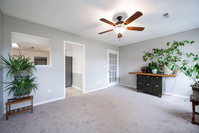 interior space with carpet, visible vents, a ceiling fan, a textured ceiling, and baseboards