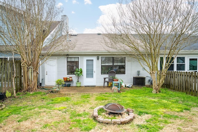 rear view of house with a yard, an outdoor fire pit, cooling unit, and fence