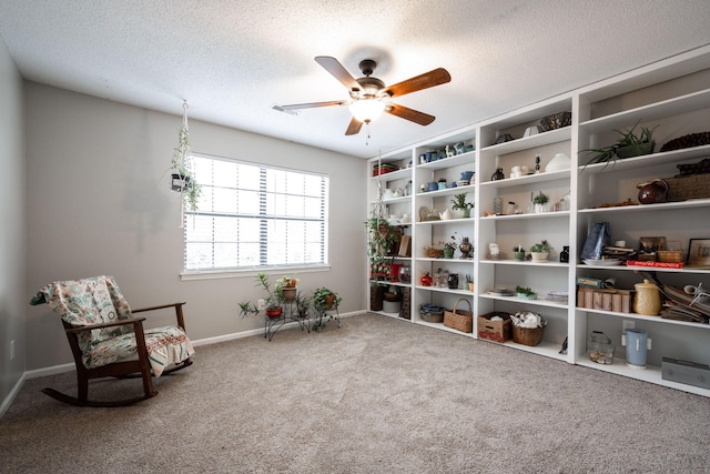 sitting room featuring a textured ceiling, carpet floors, a ceiling fan, and baseboards