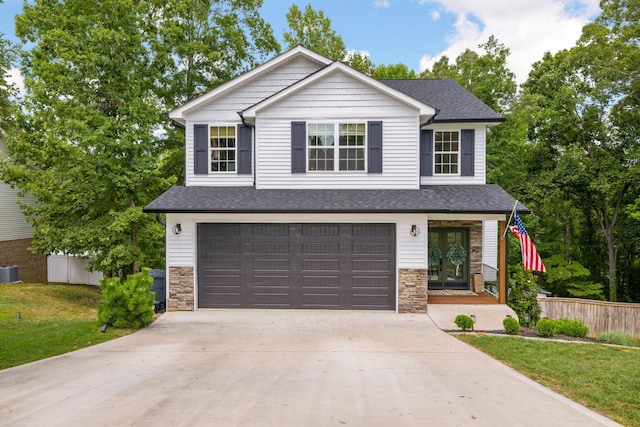 view of front of home with a garage, central AC, and a front yard