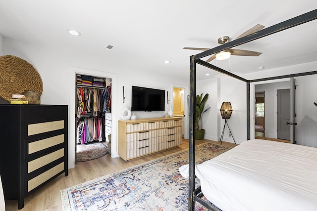 bedroom with a closet, a spacious closet, ceiling fan, and light hardwood / wood-style flooring