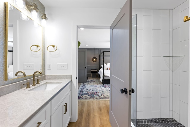 bathroom featuring hardwood / wood-style flooring, vanity, and a tile shower