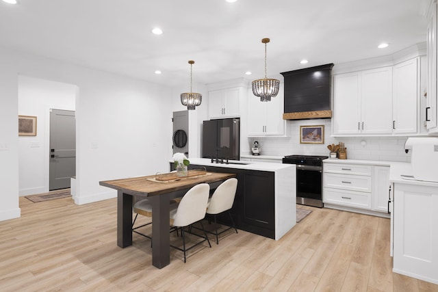 kitchen featuring white cabinetry, a center island, pendant lighting, and stainless steel stove