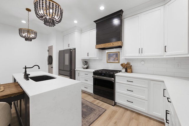 kitchen featuring range with gas stovetop, an island with sink, white cabinets, fridge, and custom exhaust hood