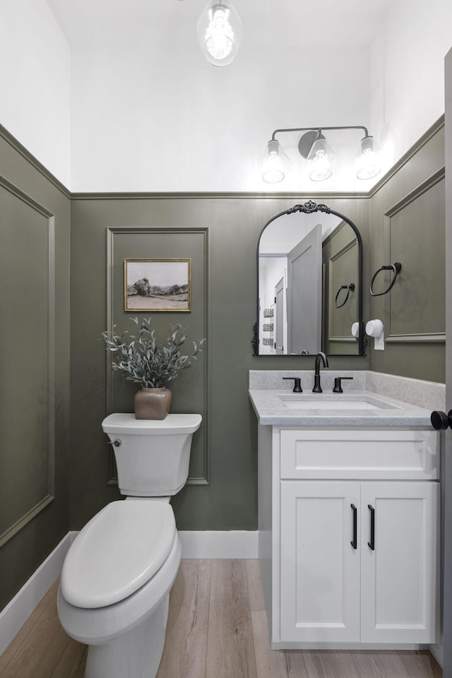 bathroom with toilet, vanity, and wood-type flooring