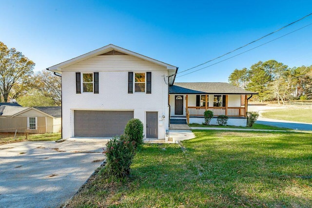 split level home with a garage, a front yard, covered porch, and driveway