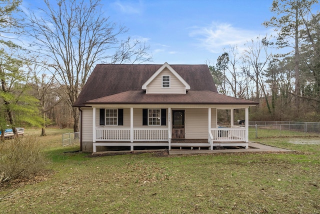 farmhouse featuring covered porch, a front lawn, and fence