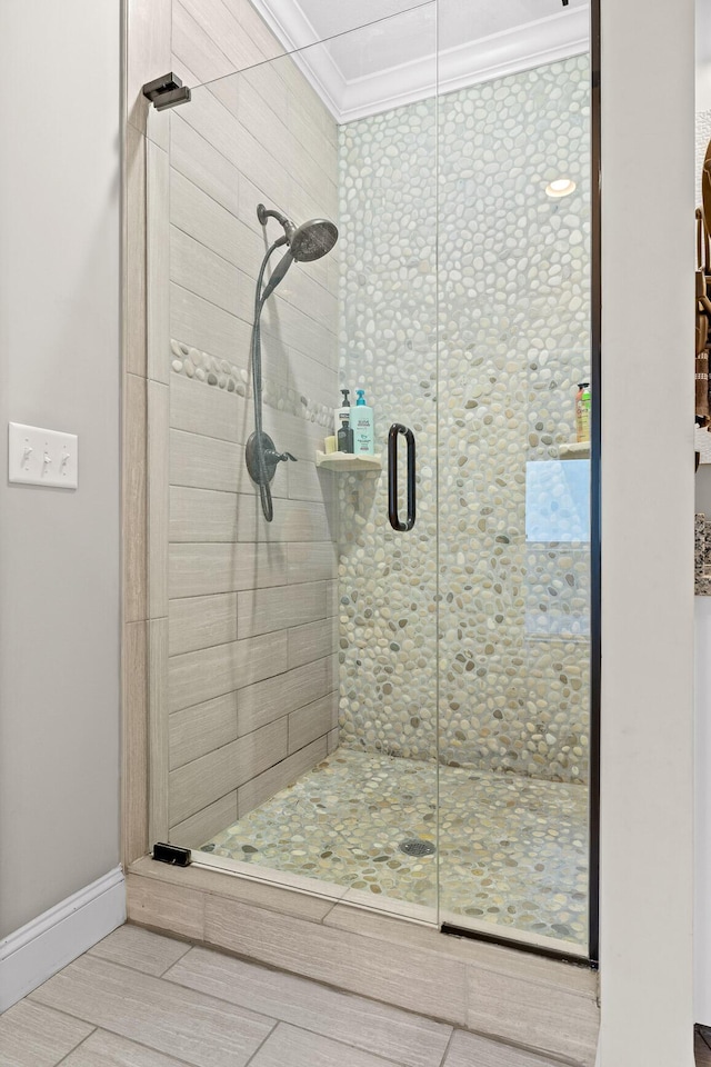 bathroom featuring ornamental molding, a shower stall, and baseboards