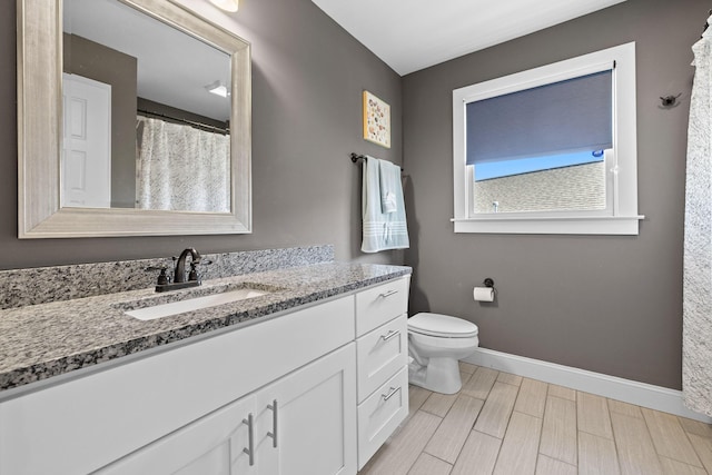 bathroom with toilet, wood tiled floor, baseboards, and vanity