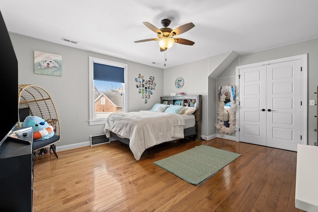 bedroom with wood-type flooring, visible vents, a closet, a ceiling fan, and baseboards