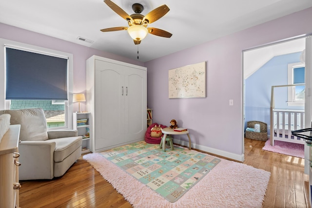 interior space featuring a ceiling fan, light wood-style flooring, visible vents, and baseboards