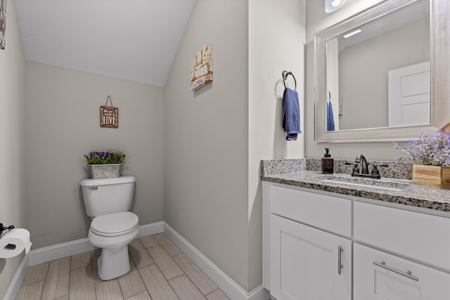 half bath featuring baseboards, toilet, lofted ceiling, vanity, and wood finish floors