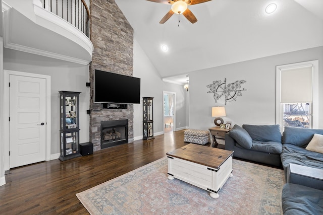 living room with dark wood-style flooring, ceiling fan, a stone fireplace, high vaulted ceiling, and baseboards