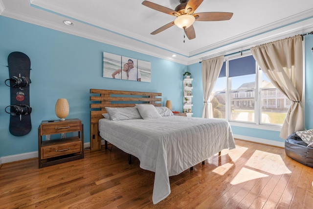 bedroom featuring baseboards, wood finished floors, and crown molding