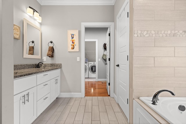 bathroom featuring wood tiled floor, a washtub, crown molding, vanity, and separate washer and dryer