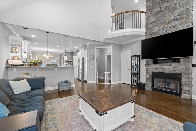 living room with crown molding, dark wood finished floors, a stone fireplace, and baseboards