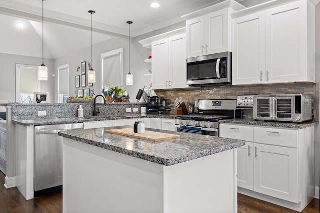 kitchen with a peninsula, a kitchen island, white cabinetry, and stainless steel appliances