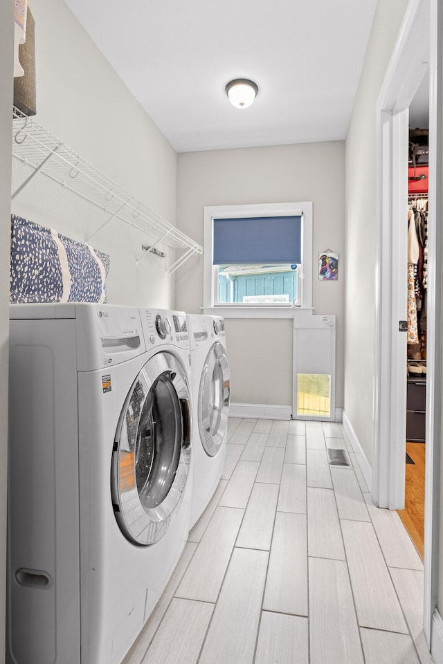 washroom featuring washing machine and dryer, laundry area, and baseboards