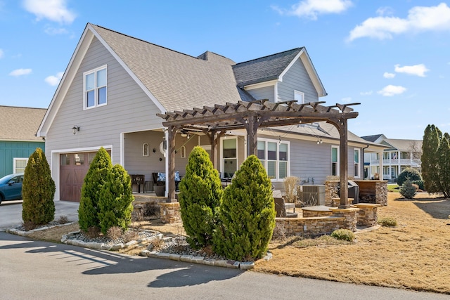 view of front facade with covered porch, roof with shingles, an attached garage, and a pergola