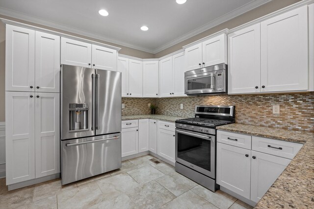 kitchen featuring white cabinets, stainless steel appliances, light stone counters, and ornamental molding