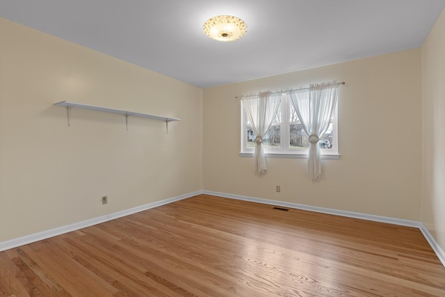 empty room with light wood finished floors, baseboards, and visible vents