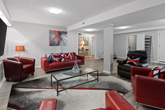 living room with a textured ceiling, baseboards, and wood finished floors