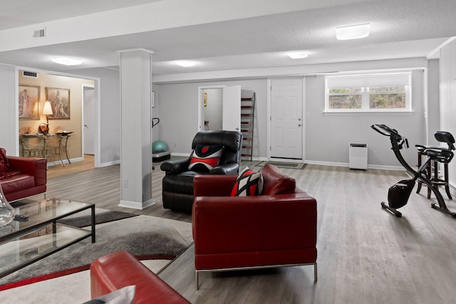 living room featuring baseboards, a textured ceiling, visible vents, and wood finished floors
