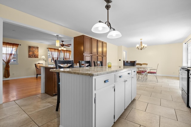 kitchen with brown cabinets, decorative light fixtures, a center island, and light tile patterned floors