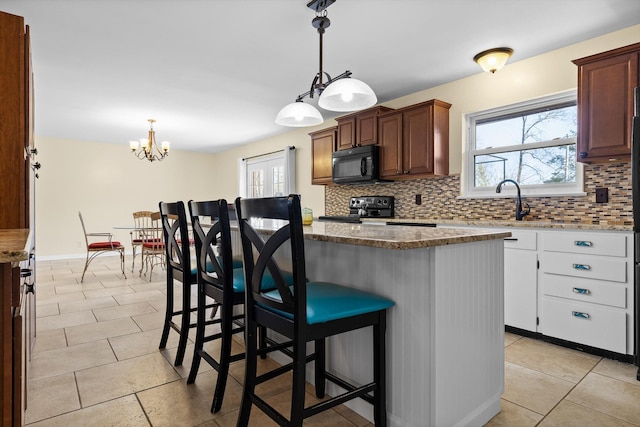kitchen featuring decorative backsplash, range with electric cooktop, black microwave, and a center island