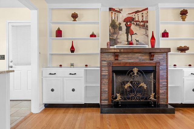 unfurnished living room featuring light wood finished floors, a fireplace, and built in features