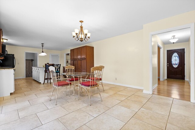 dining space featuring light tile patterned floors, baseboards, and a chandelier