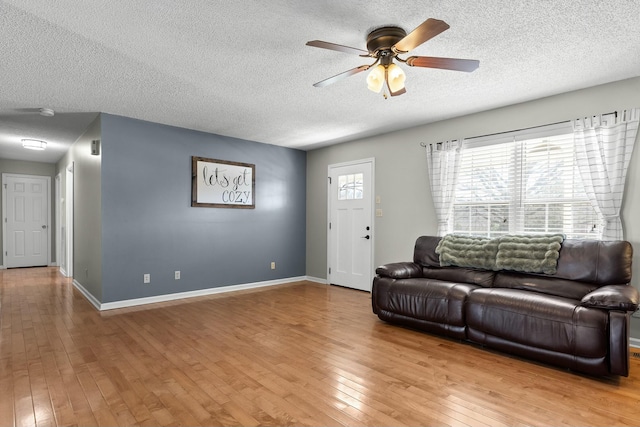 living area with baseboards, ceiling fan, and hardwood / wood-style flooring