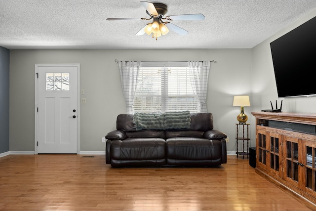 living area with plenty of natural light, light wood-style floors, and ceiling fan