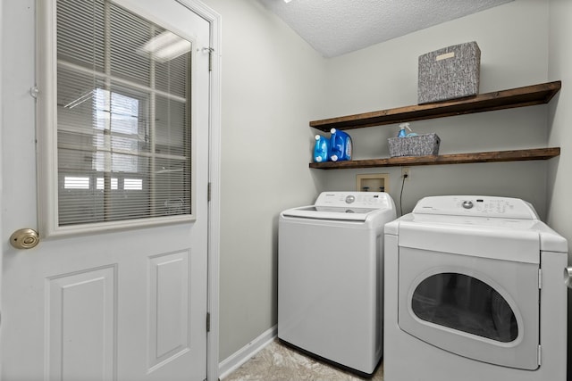 washroom featuring a textured ceiling, laundry area, baseboards, and washer and clothes dryer