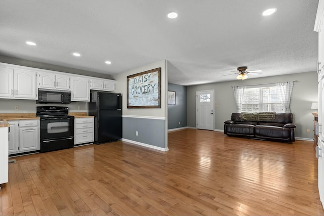 kitchen with light wood finished floors, open floor plan, white cabinetry, and black appliances