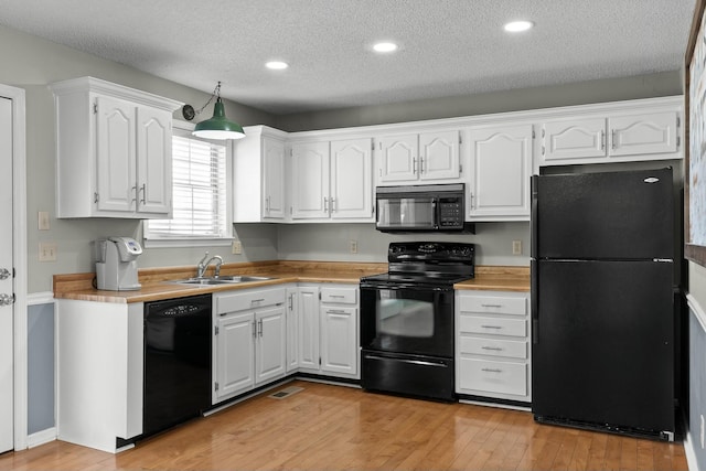 kitchen featuring visible vents, a sink, black appliances, white cabinets, and light wood-style floors