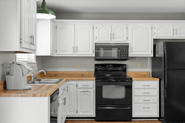 kitchen with a textured ceiling, a sink, black appliances, pendant lighting, and white cabinetry