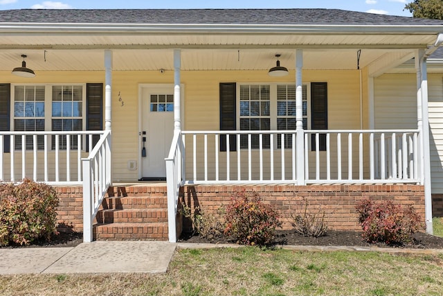 doorway to property featuring covered porch and brick siding