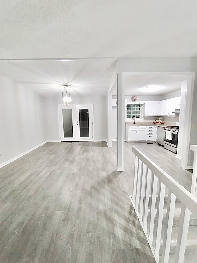 unfurnished living room featuring sink, a chandelier, and light hardwood / wood-style flooring