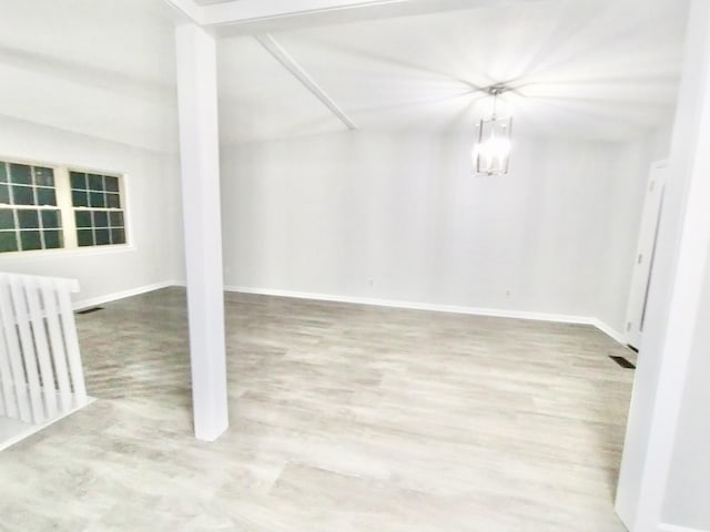 spare room with radiator heating unit, an inviting chandelier, and hardwood / wood-style flooring