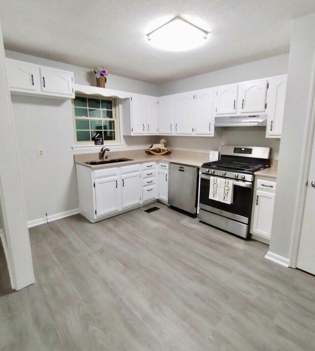 kitchen with sink, stainless steel range with gas cooktop, white cabinetry, dishwasher, and light hardwood / wood-style flooring