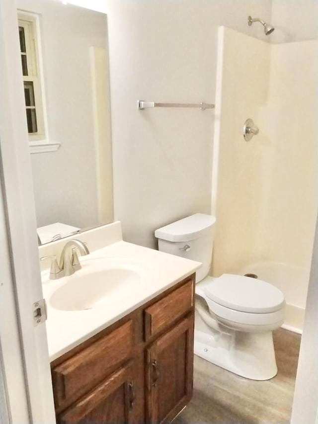 bathroom featuring hardwood / wood-style floors, walk in shower, vanity, and toilet